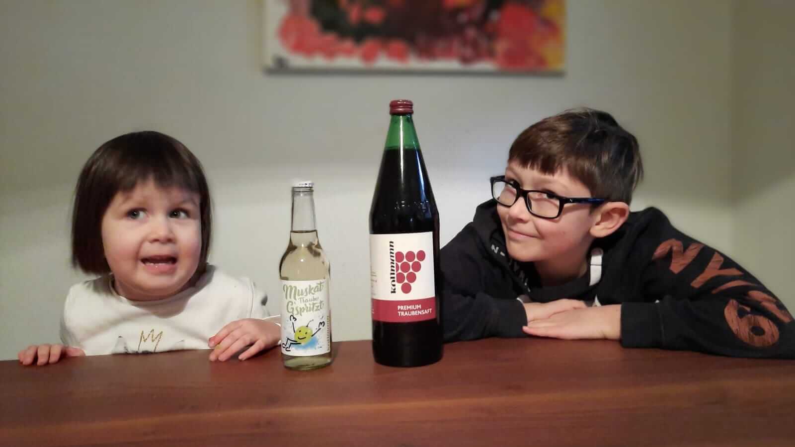 Zwei Kinder, die Fruchtsäfte von Kollmann brennt trinken.