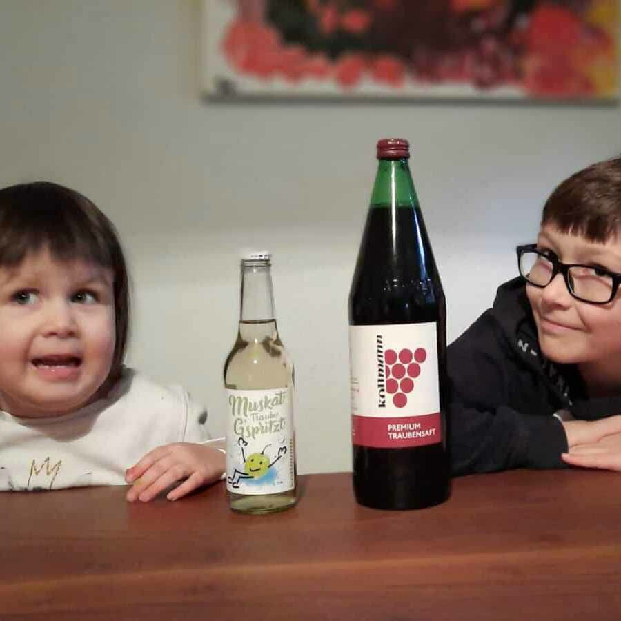 Zwei Kinder, die Fruchtsäfte von Kollmann brennt trinken.
